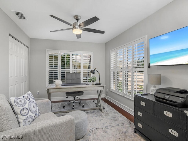 office space with a wealth of natural light, wood finished floors, ceiling fan, and baseboards