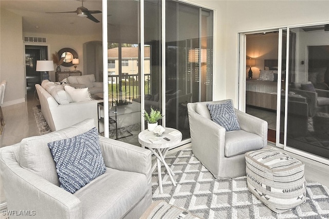 living room with a ceiling fan, visible vents, and baseboards