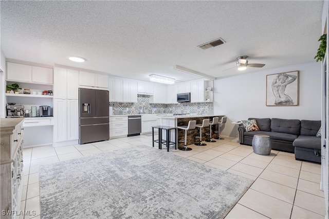 living room with a textured ceiling, light tile patterned floors, and ceiling fan