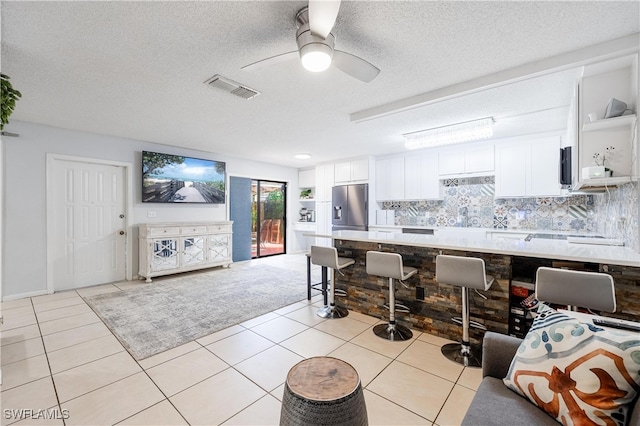 kitchen with white cabinets, light tile patterned flooring, a textured ceiling, backsplash, and stainless steel refrigerator with ice dispenser