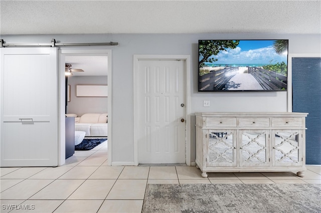 tiled entryway with a textured ceiling, ceiling fan, and a barn door