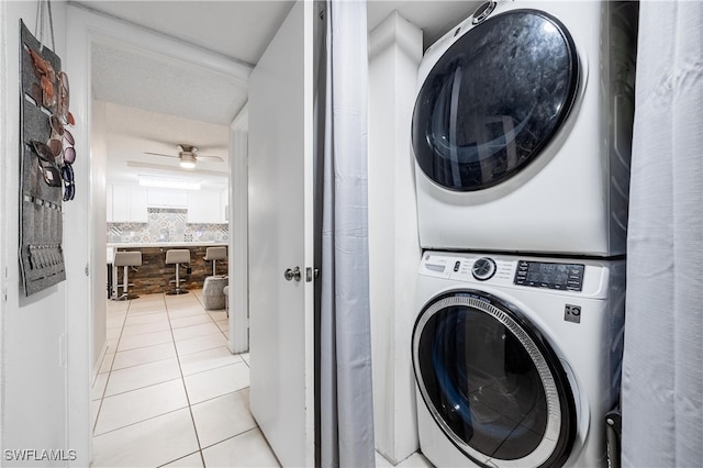 laundry area featuring ceiling fan, light tile patterned floors, a textured ceiling, and stacked washer / drying machine