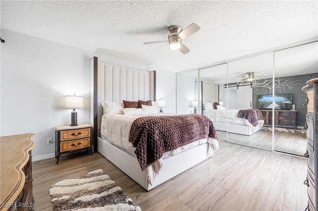 bedroom with a closet, ceiling fan, hardwood / wood-style flooring, and a textured ceiling