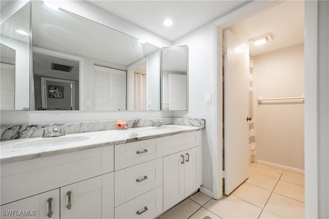 bathroom with a textured ceiling, vanity, and tile patterned floors