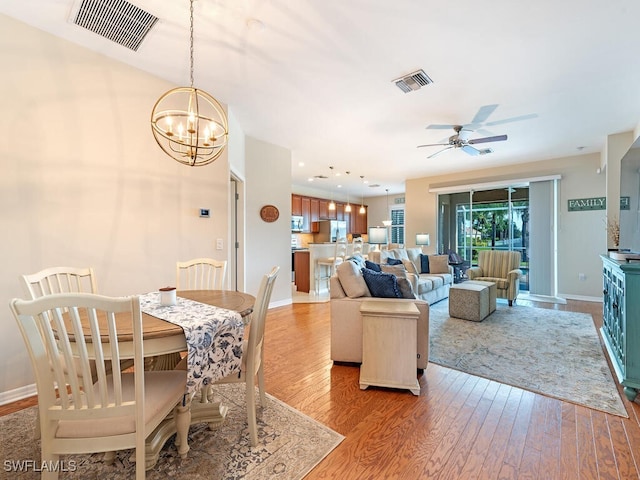 dining room with ceiling fan with notable chandelier and wood-type flooring