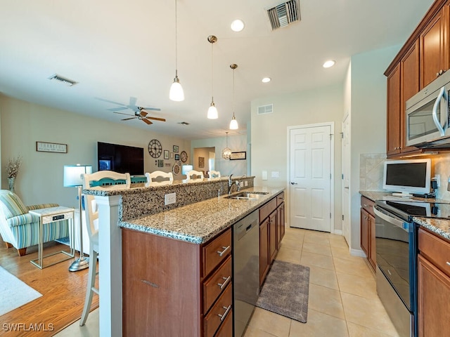 kitchen featuring a breakfast bar, sink, hanging light fixtures, stainless steel appliances, and ceiling fan