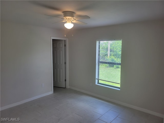 empty room with light tile patterned floors, ceiling fan, and a wealth of natural light