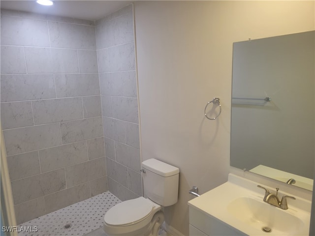 bathroom featuring vanity, toilet, and tiled shower