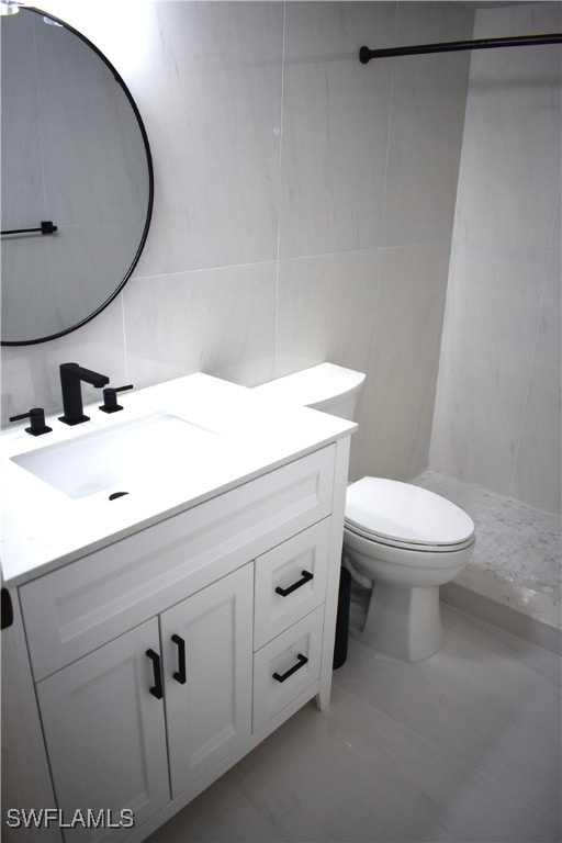 bathroom featuring tile walls, a shower, tile patterned floors, vanity, and toilet