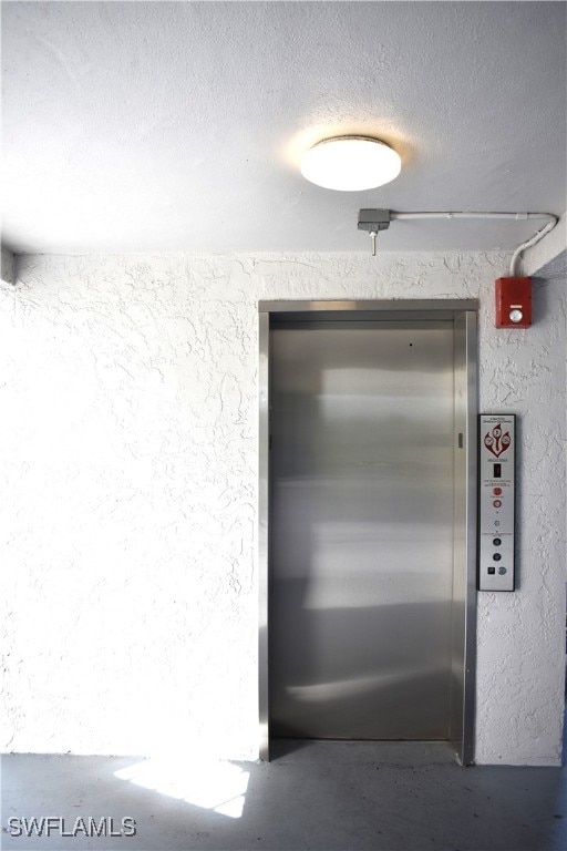 details with a textured ceiling, concrete floors, and elevator