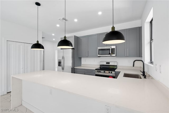 kitchen featuring gray cabinetry, sink, appliances with stainless steel finishes, decorative light fixtures, and kitchen peninsula