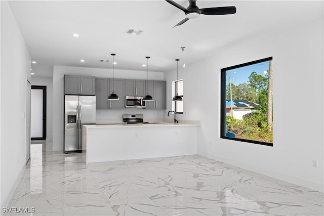 kitchen featuring kitchen peninsula, appliances with stainless steel finishes, gray cabinetry, ceiling fan, and hanging light fixtures