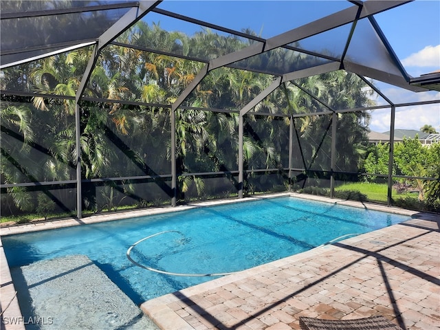 view of swimming pool with glass enclosure and a patio