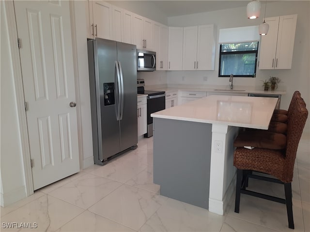 kitchen with sink, a breakfast bar area, white cabinetry, stainless steel appliances, and decorative light fixtures