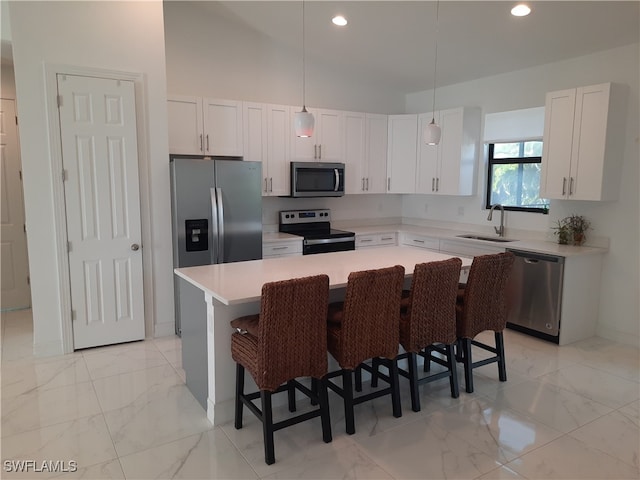 kitchen with white cabinets, pendant lighting, sink, a kitchen island, and appliances with stainless steel finishes