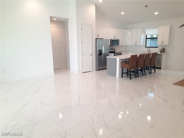 kitchen featuring sink, white cabinetry, appliances with stainless steel finishes, a kitchen breakfast bar, and a center island