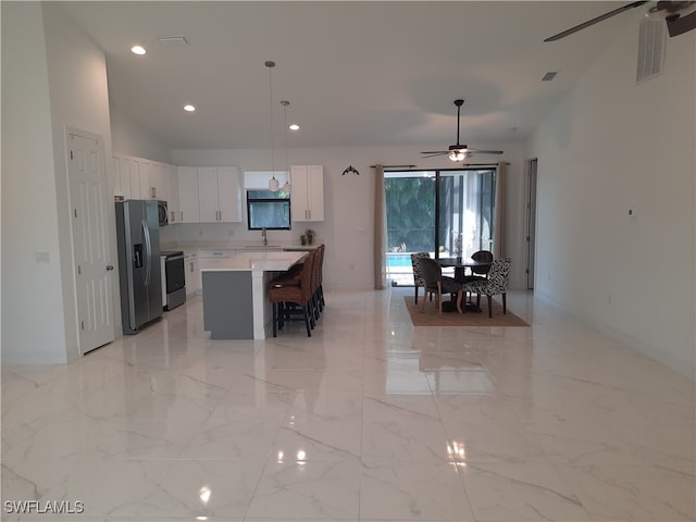 kitchen with a center island, white cabinetry, hanging light fixtures, appliances with stainless steel finishes, and ceiling fan