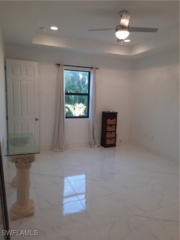 unfurnished room featuring ceiling fan and a tray ceiling