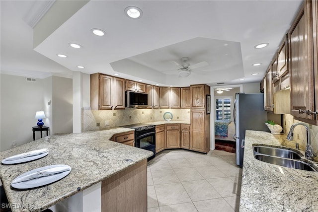 kitchen with kitchen peninsula, sink, light stone counters, and appliances with stainless steel finishes