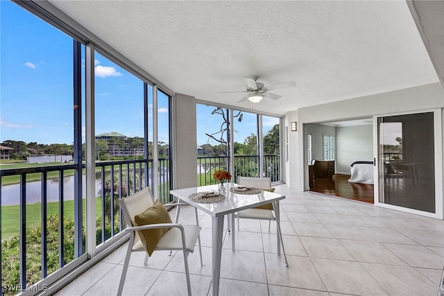 sunroom / solarium with a wealth of natural light, a water view, and ceiling fan