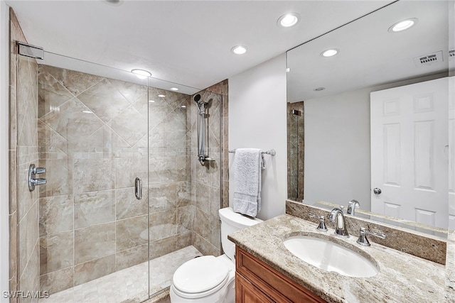 bathroom featuring a shower with shower door, vanity, and toilet