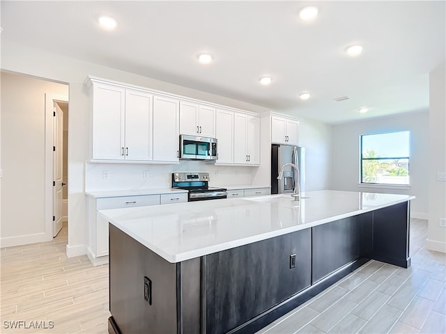 kitchen with a large island, sink, white cabinets, and appliances with stainless steel finishes