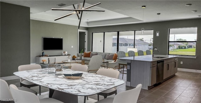 tiled dining room with a raised ceiling, sink, and an inviting chandelier