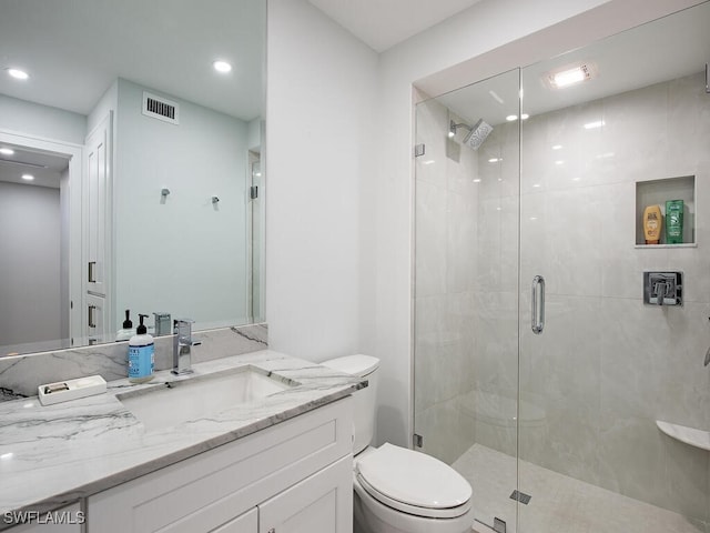 bathroom with vanity, a shower with shower door, and toilet