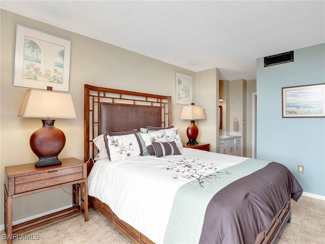 bedroom featuring a textured ceiling, ensuite bathroom, and light tile patterned flooring