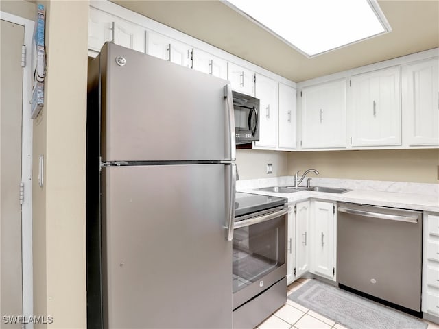 kitchen with light tile patterned floors, stainless steel appliances, white cabinetry, and sink