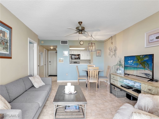 tiled living room featuring ceiling fan and a textured ceiling