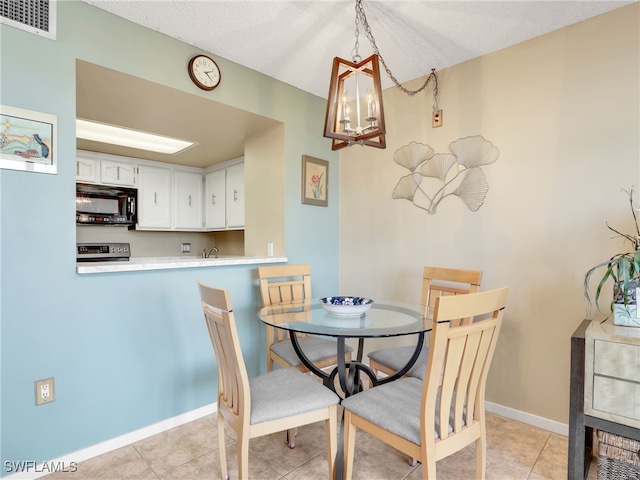 dining room with a textured ceiling, a notable chandelier, and light tile patterned flooring