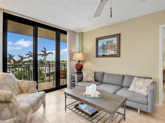 living room with ceiling fan, a wall of windows, light tile patterned floors, and a textured ceiling