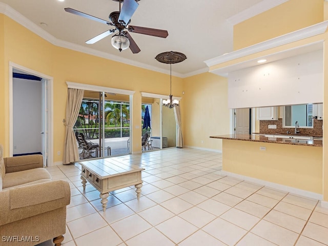 tiled living room with sink, ceiling fan with notable chandelier, and ornamental molding