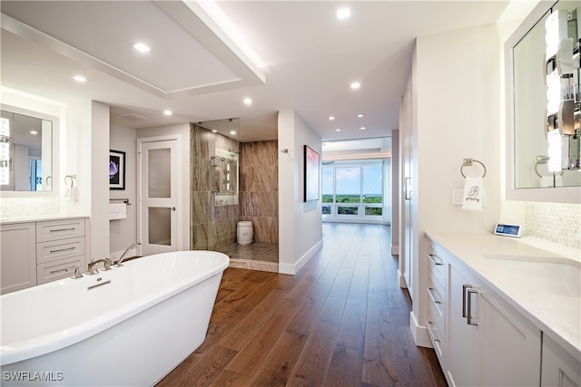 bathroom with hardwood / wood-style floors, vanity, and shower with separate bathtub