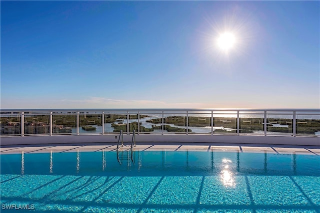 pool at dusk featuring a water view