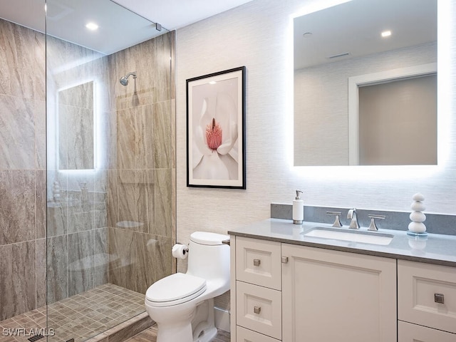 bathroom featuring vanity, toilet, and a tile shower