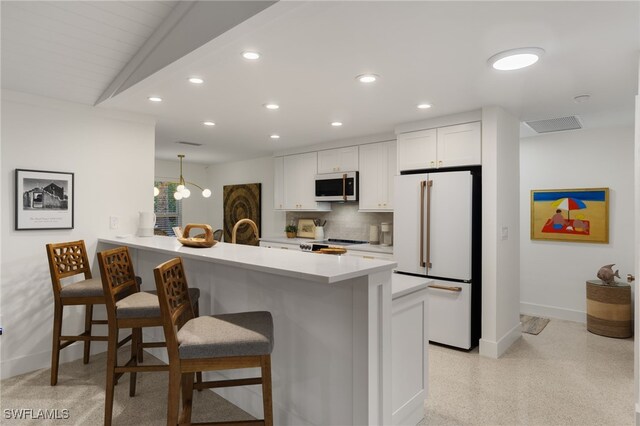 kitchen featuring a breakfast bar area, lofted ceiling, white cabinetry, kitchen peninsula, and stainless steel appliances