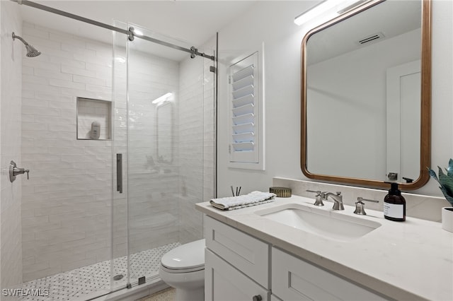 bathroom with a shower with door, vanity, and toilet