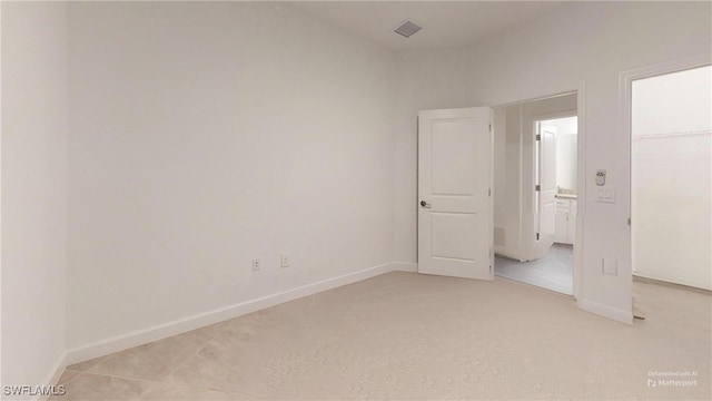 unfurnished bedroom with a walk in closet, a closet, and light colored carpet