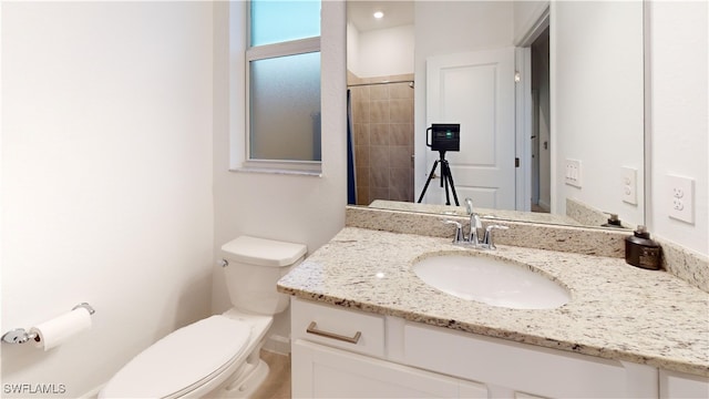 bathroom with tiled shower, vanity, and toilet