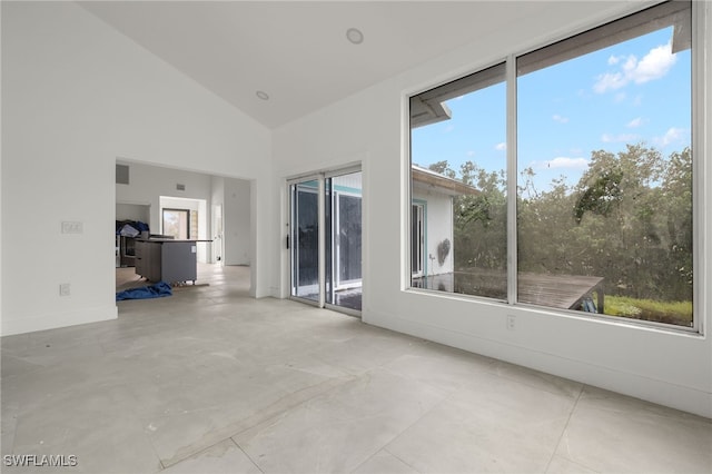 unfurnished living room with high vaulted ceiling and a healthy amount of sunlight