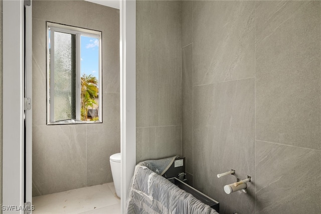 bathroom featuring tile walls and toilet