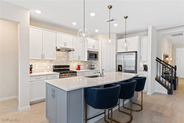 kitchen featuring an island with sink, sink, stainless steel appliances, and white cabinets