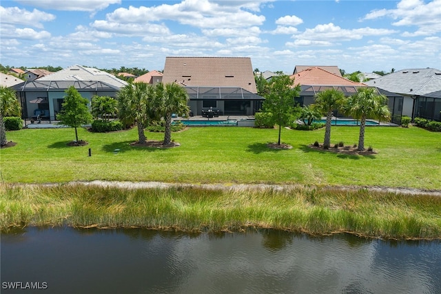 rear view of house featuring a lawn, glass enclosure, and a water view