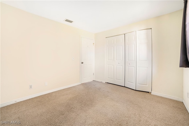 unfurnished bedroom featuring a closet and light colored carpet