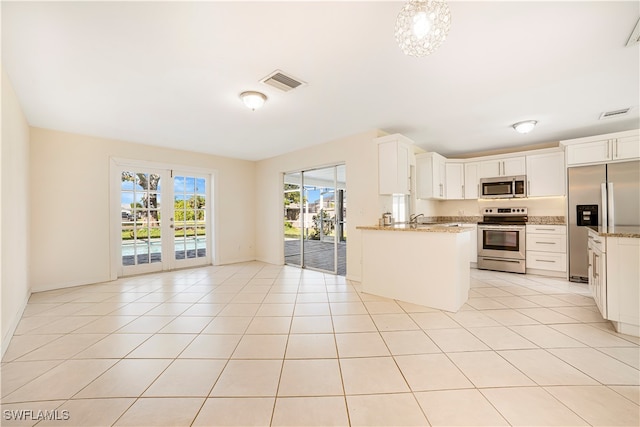 kitchen with stainless steel appliances, light stone counters, white cabinets, sink, and light tile patterned flooring