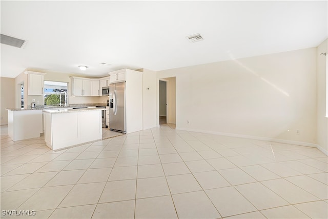 kitchen with white cabinetry, appliances with stainless steel finishes, light tile patterned floors, and a kitchen island