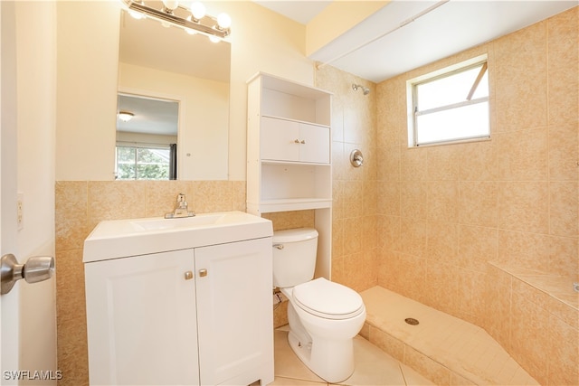 bathroom with tile patterned flooring, a tile shower, vanity, toilet, and tile walls