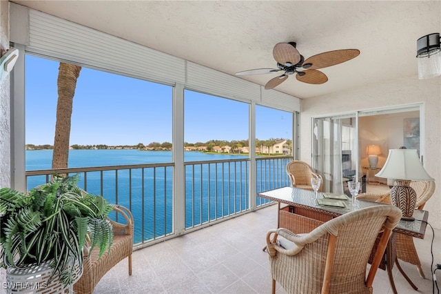 sunroom / solarium with a water view and ceiling fan